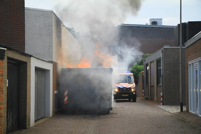 Vlammen slaan uit bouwcontainer met afval