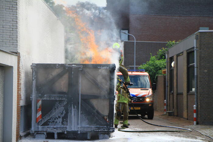 Vlammen slaan uit bouwcontainer met afval