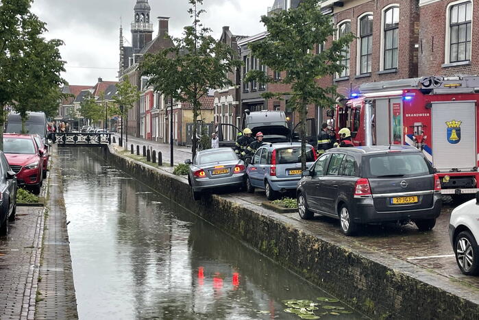 Auto bengelt op rand van gracht