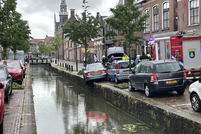 Auto bengelt op rand van gracht