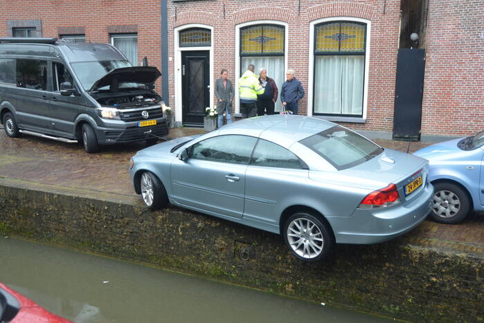 Auto bengelt op rand van gracht