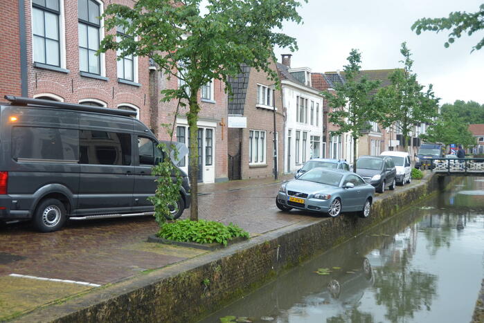 Auto bengelt op rand van gracht