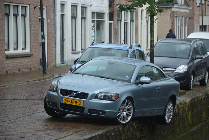 Auto bengelt op rand van gracht