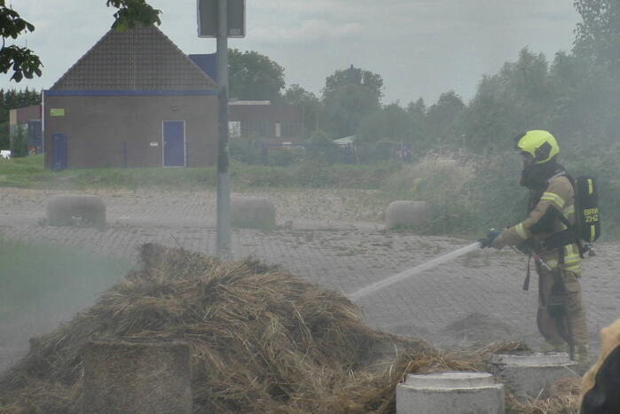 Brandweer blust brandende hooibaal