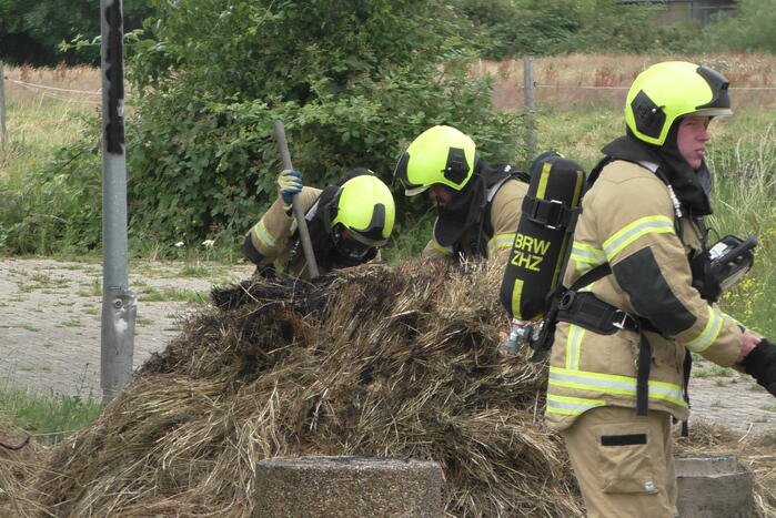 Brandweer blust brandende hooibaal
