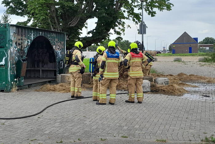 Brandweer blust brandende hooibaal