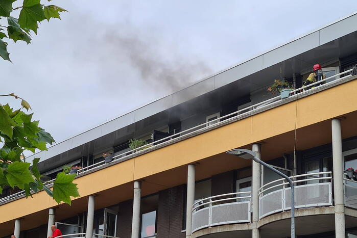 Zwarte rook uit appartement vanwege brand