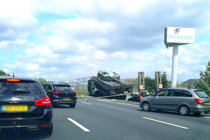 Vrachtwagen met gevechtstank boort zich in geluidswal