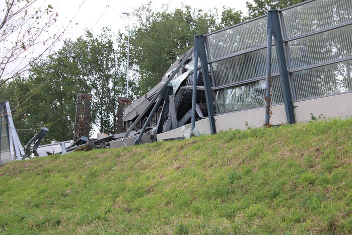 Vrachtwagen met gevechtstank boort zich in geluidswal