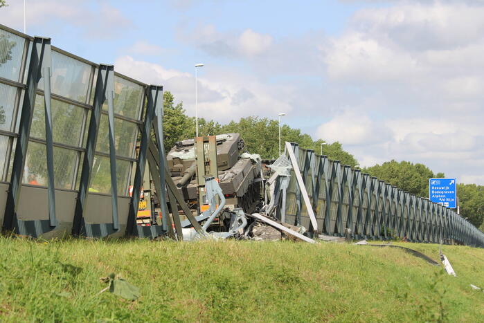 Vrachtwagen met gevechtstank boort zich in geluidswal