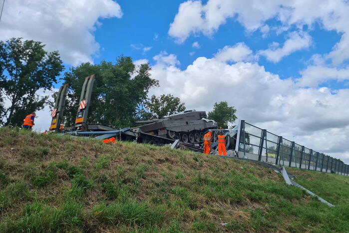 Vrachtwagen met gevechtstank boort zich in geluidswal