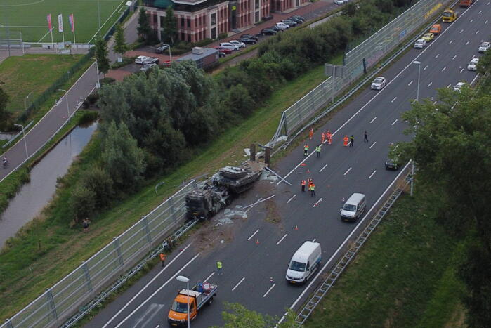 Vrachtwagen met gevechtstank boort zich in geluidswal