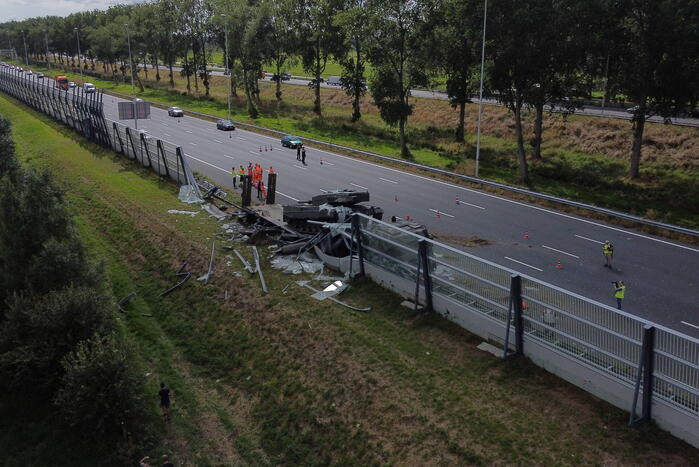 Vrachtwagen met gevechtstank boort zich in geluidswal