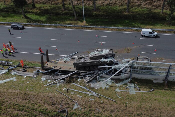 Vrachtwagen met gevechtstank boort zich in geluidswal