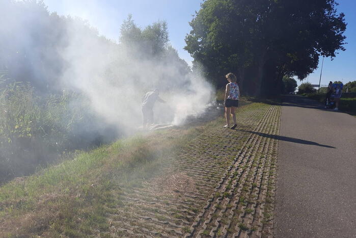 Omstanders doven bermbrand met kleed