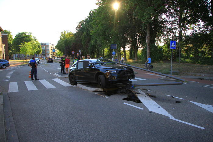 Personenauto uit de bocht, lantaarnpaal geraakt