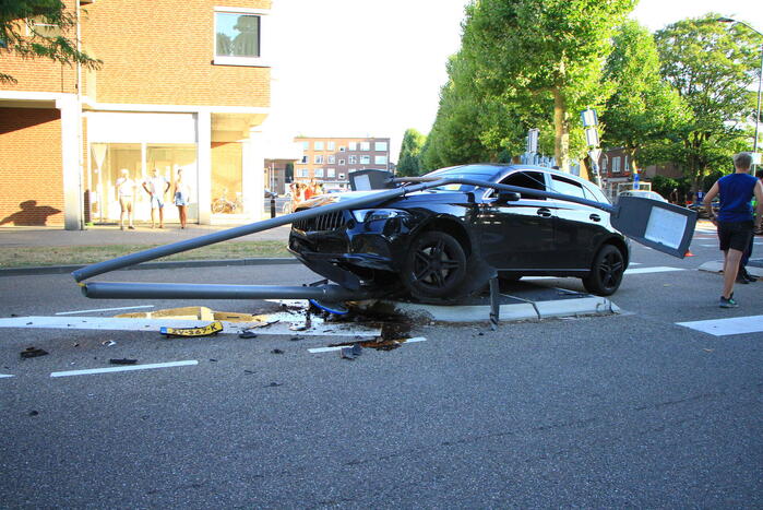 Personenauto uit de bocht, lantaarnpaal geraakt