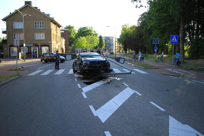 Personenauto uit de bocht, lantaarnpaal geraakt