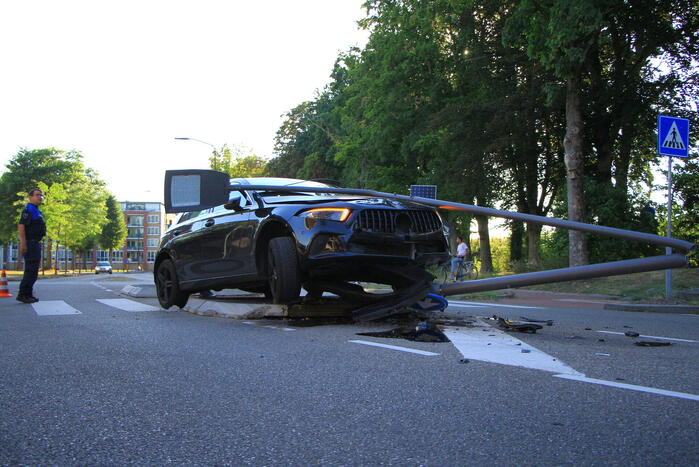 Personenauto uit de bocht, lantaarnpaal geraakt