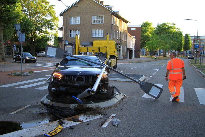 Personenauto uit de bocht, lantaarnpaal geraakt