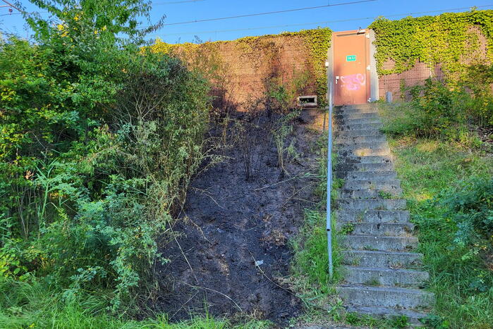 Brandweer blust bermbrand naast treinspoor