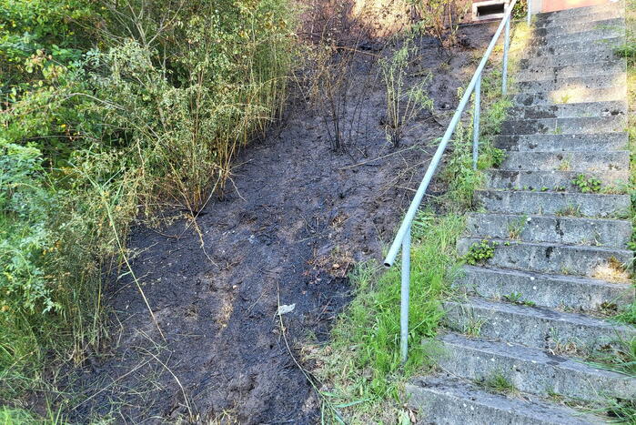 Brandweer blust bermbrand naast treinspoor