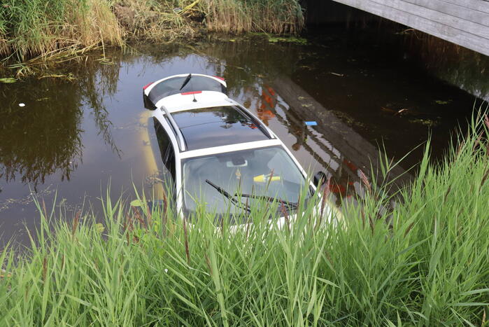 Auto raakt te water naast brug
