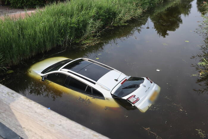 Auto raakt te water naast brug