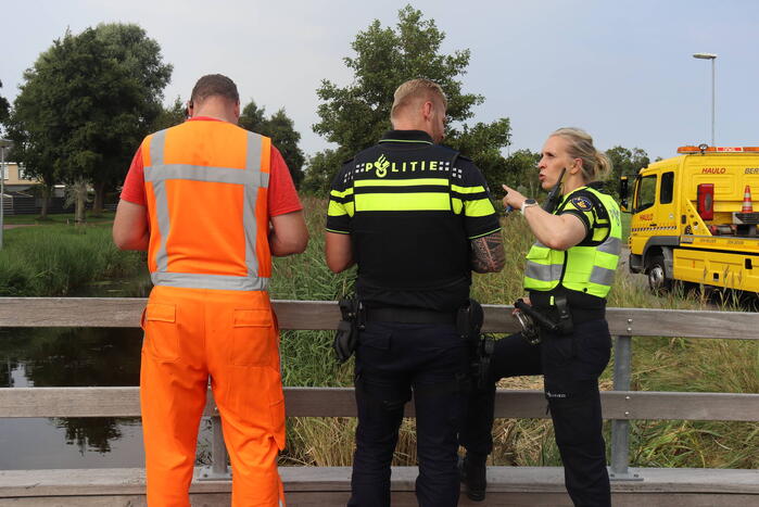 Auto raakt te water naast brug