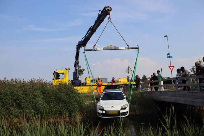 Auto raakt te water naast brug