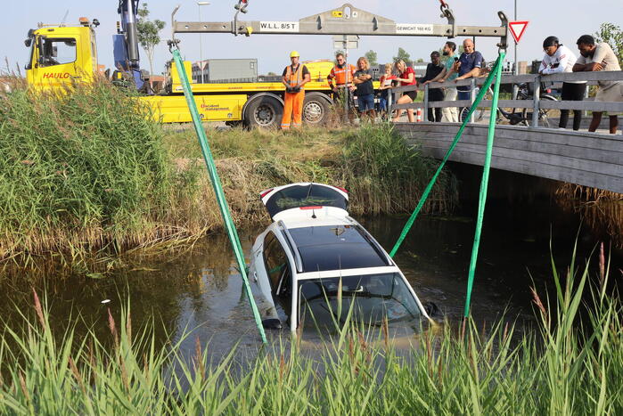Auto raakt te water naast brug