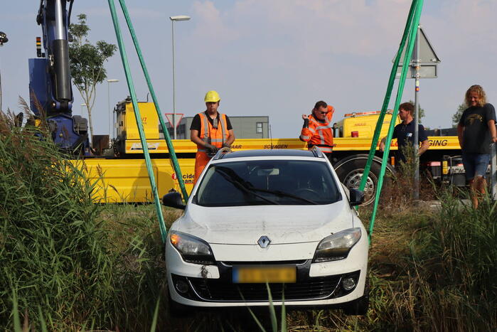 Auto raakt te water naast brug