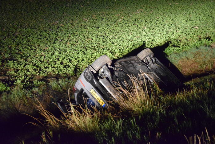 Auto op zijn kop in sloot naast talud