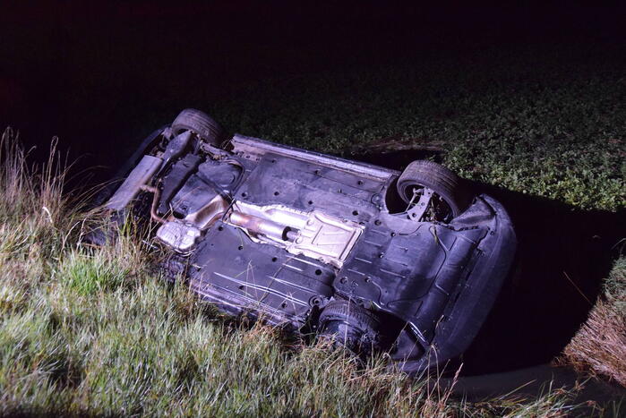 Auto op zijn kop in sloot naast talud