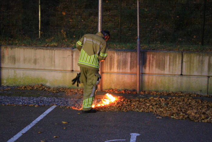 Bladeren vliegen in brand op parkeerterrein