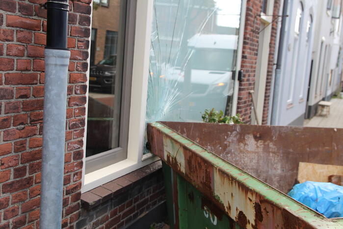 Pakketbezorger botst tegen bouwcontainer en knalt tegen woning