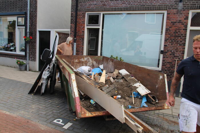 Pakketbezorger botst tegen bouwcontainer en knalt tegen woning