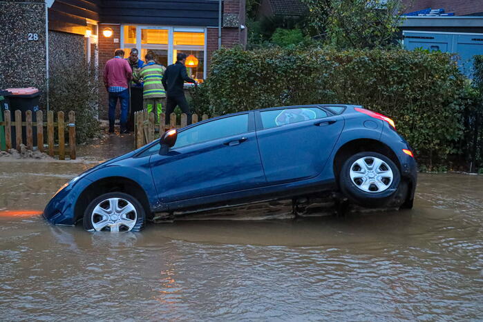 Auto zakt in sinkhole door gesprongen hoofdwaterleiding