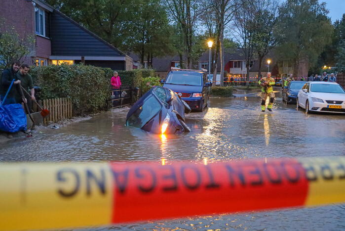 Auto zakt in sinkhole door gesprongen hoofdwaterleiding