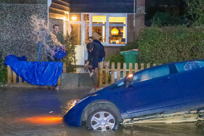 Auto zakt in sinkhole door gesprongen hoofdwaterleiding