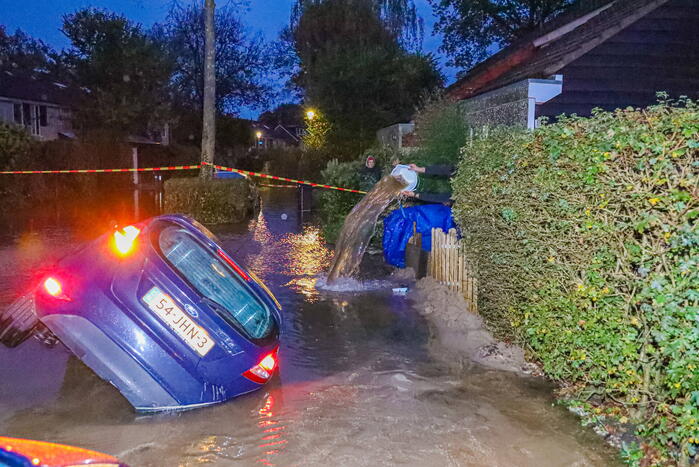Auto zakt in sinkhole door gesprongen hoofdwaterleiding