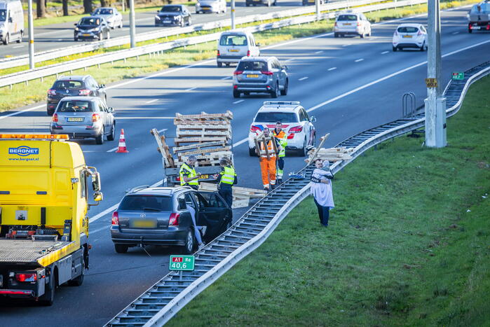 Automobilist verliest overbeladen aanhangwagen met pallets en crasht