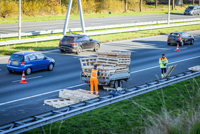 Automobilist verliest overbeladen aanhangwagen met pallets en crasht