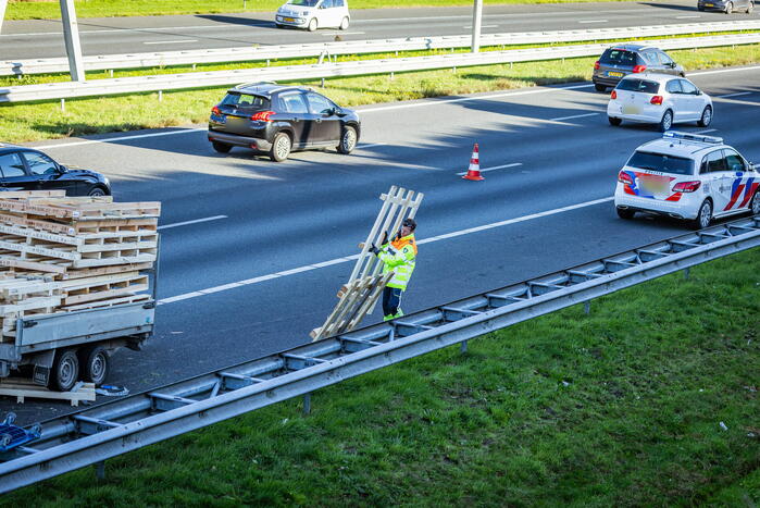Automobilist verliest overbeladen aanhangwagen met pallets en crasht