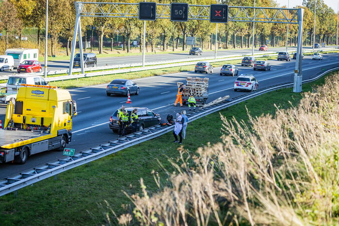 Automobilist verliest overbeladen aanhangwagen met pallets en crasht