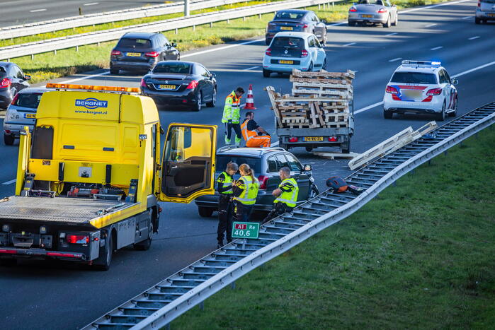 Automobilist verliest overbeladen aanhangwagen met pallets en crasht
