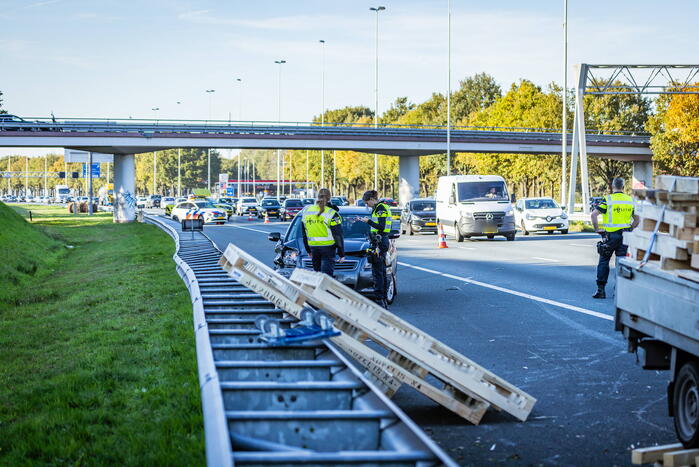 Automobilist verliest overbeladen aanhangwagen met pallets en crasht
