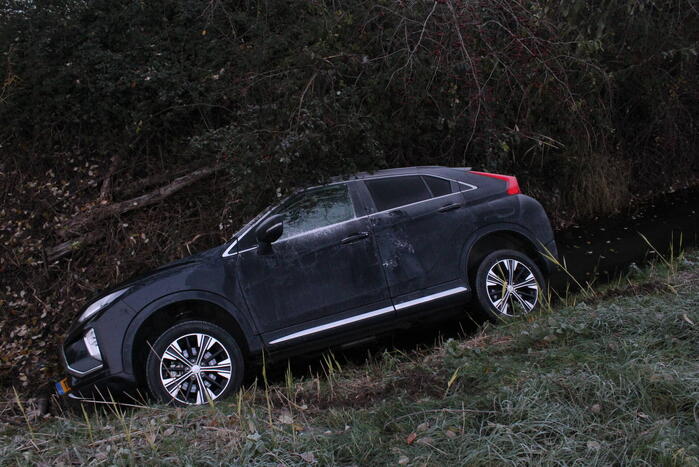 Auto raakt van de weg en belandt half in de sloot
