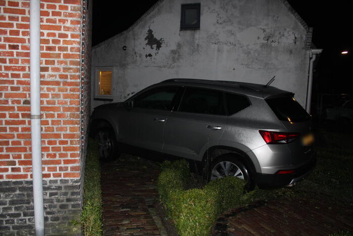 Auto glijdt door tegen woning