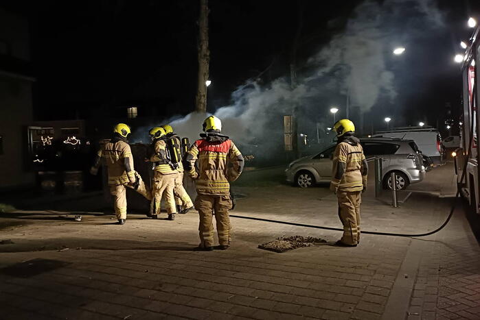 Brandweer blust in brand gestoken container